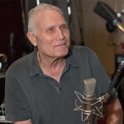 Peter Drew in a recording studio, in front of a silver microphone.